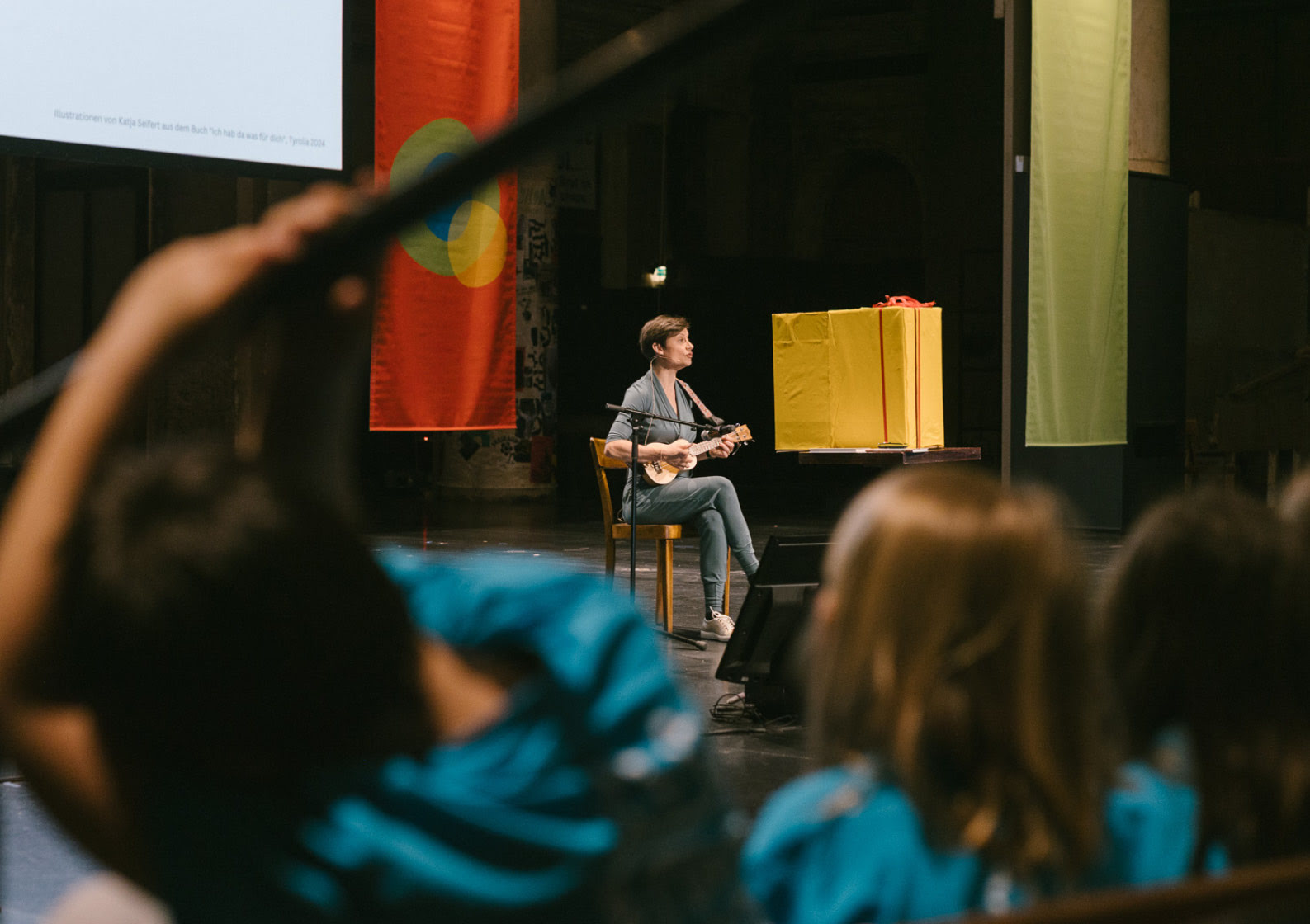 Lena Raubaum singt sitzend, live und mit Gitarre auf einer B&uuml;hne.